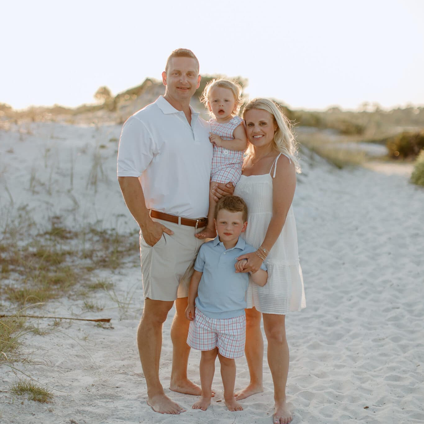 Family of four posing in the sand dunes at Johnson Beach Perdido Key during golden hour.