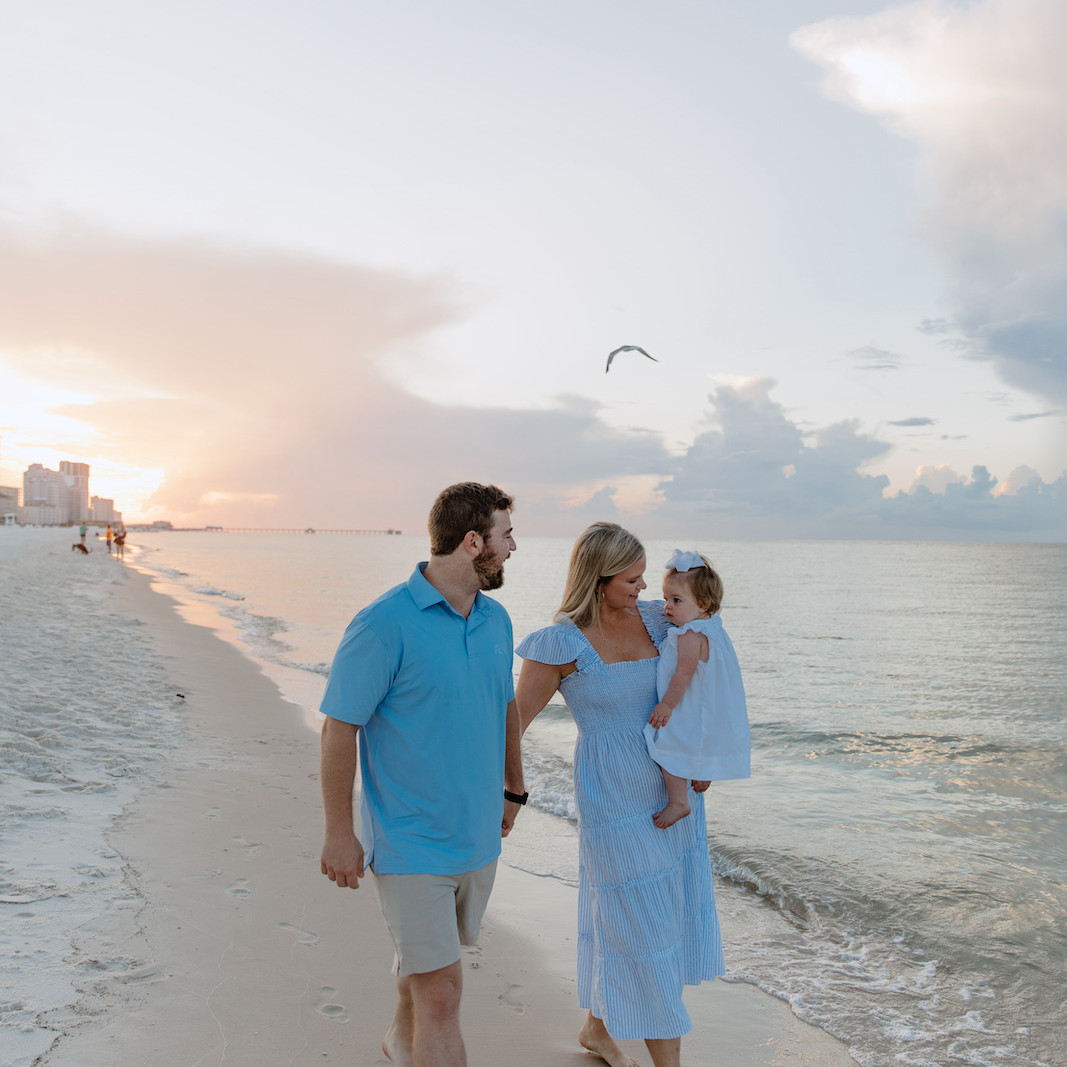 Father, mother, and baby posing for a portrait in Gulf Shores, Alabama by Shore Shooters