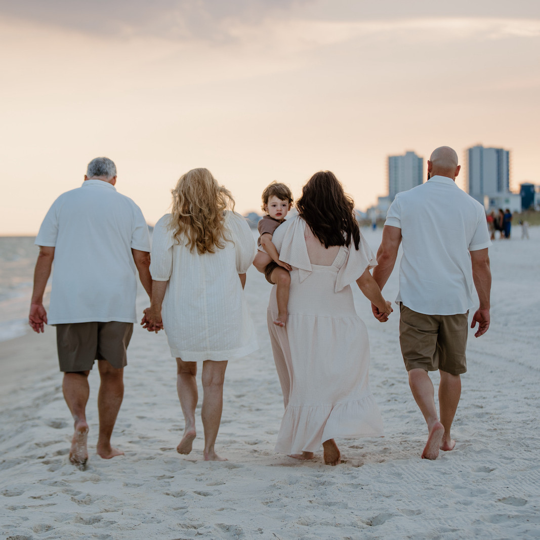 A large multi-generational family dressed in coordinated blue and white outfits standing together in Orange Beach for a portrait.